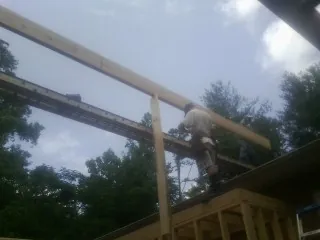Carpenter setting a ridge beam over a new addition frame — Ice Dam Removal by Roofing Brothers in Velma