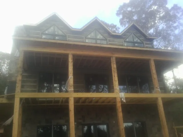 Dormers and porch framing on a large log home under construction — Roof Coating work by our crew in Velma