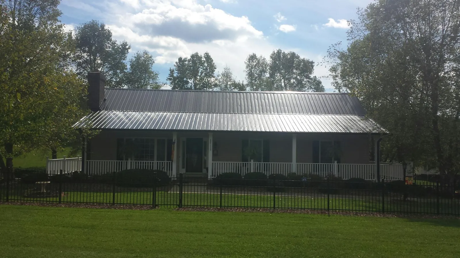 Gray metal roof on a brick ranch with a full width front porch — Gutter Guard Installation work by our crew in Velma