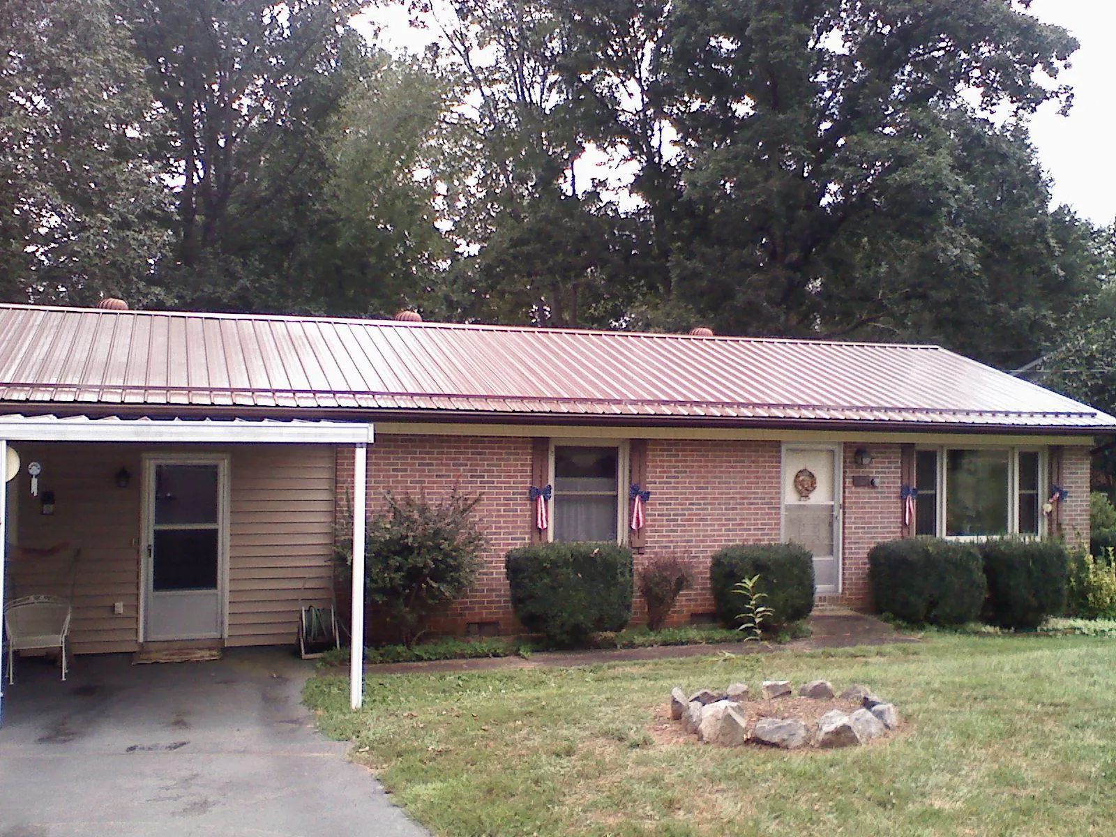 Bronze metal roof and carport on a brick ranch home — Roof Repair work by our crew in Velma